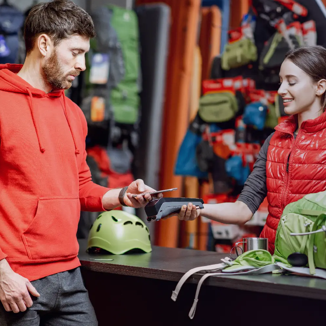 Un homme paie avec un smartphone à la caisse dans un magasin d'équipement de sport.