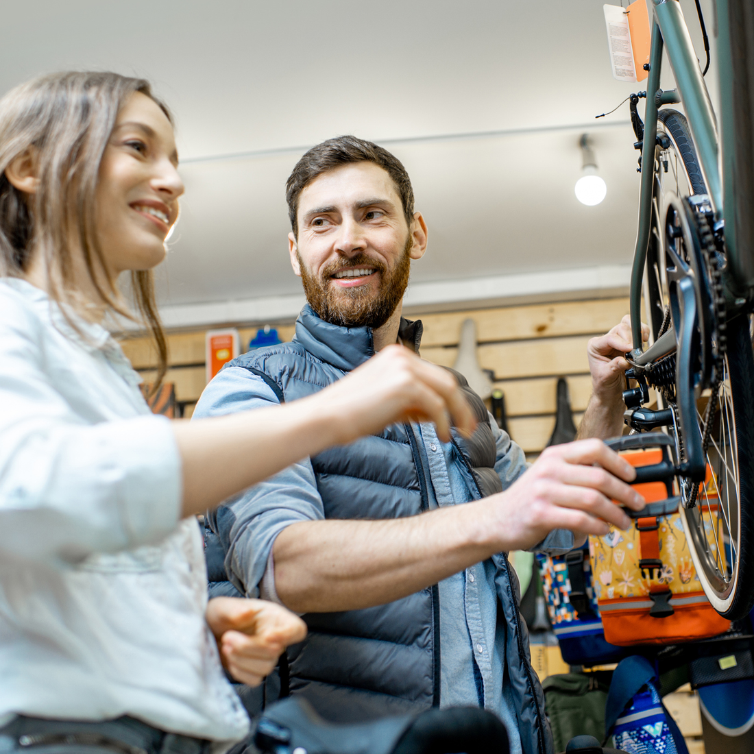 Un homme répare un vélo pendant qu'une femme sourit dans un atelier de réparation de vélos.