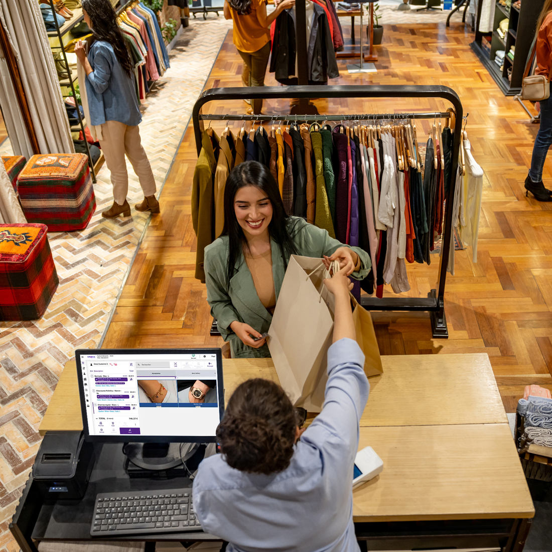 Une cliente souriante récupère un sac de shopping d’un employé à la caisse du magasin de vêtements.