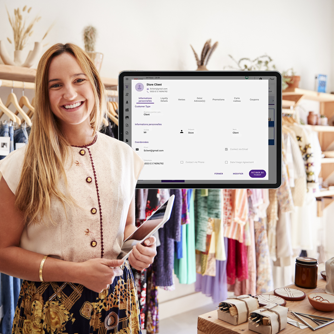 Jeune femme souriante tenant une tablette dans une boutique avec écran affichant les infos client POS.