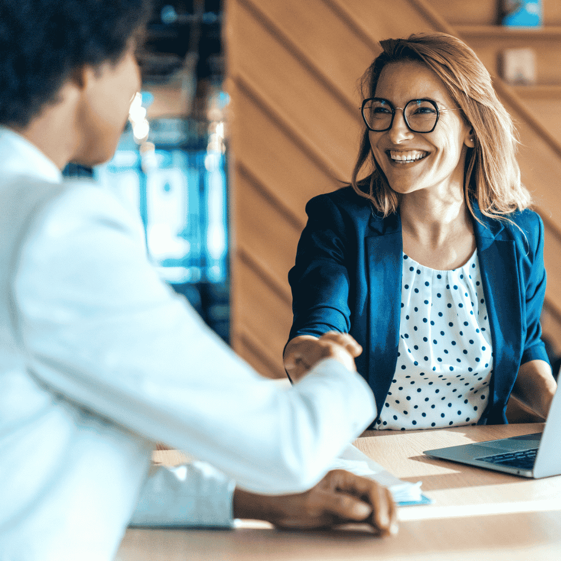 Deux professionnels se serrant la main en souriant au bureau lors d'une réunion de travail.