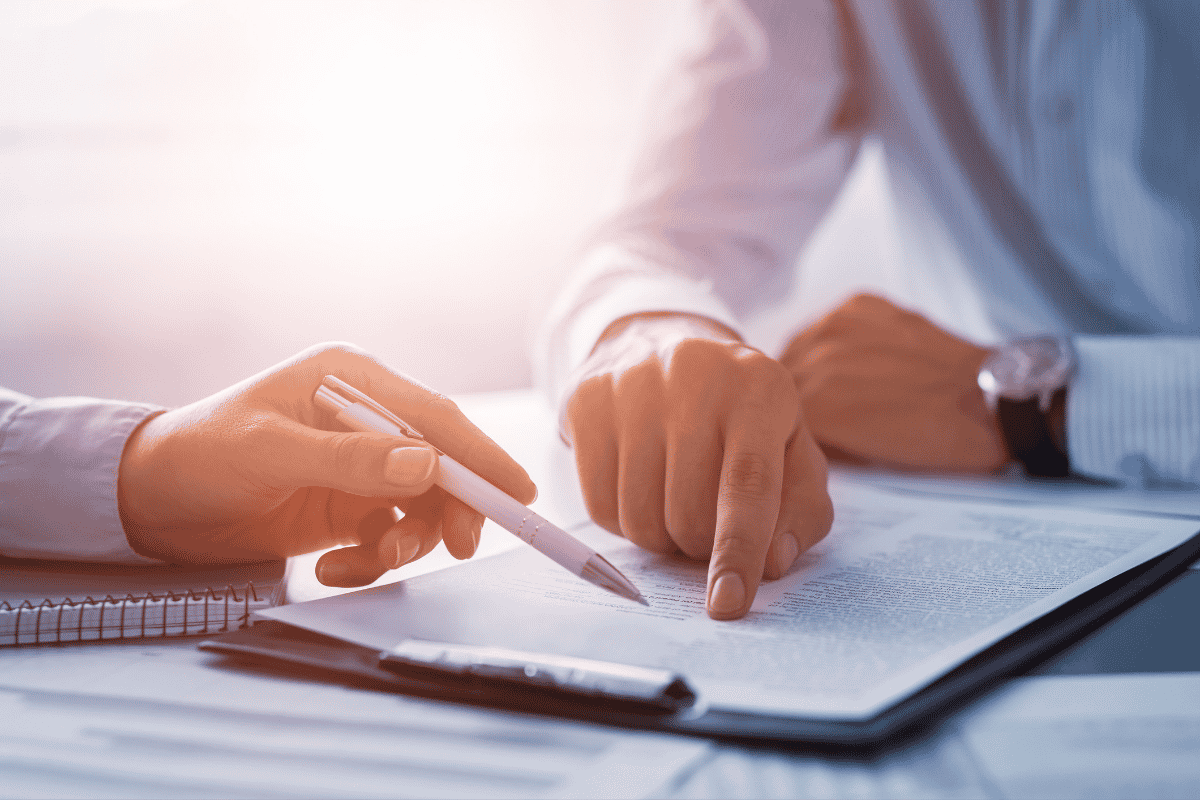 Deux personnes examinent un document, une pointe du doigt et l’autre tient un stylo.