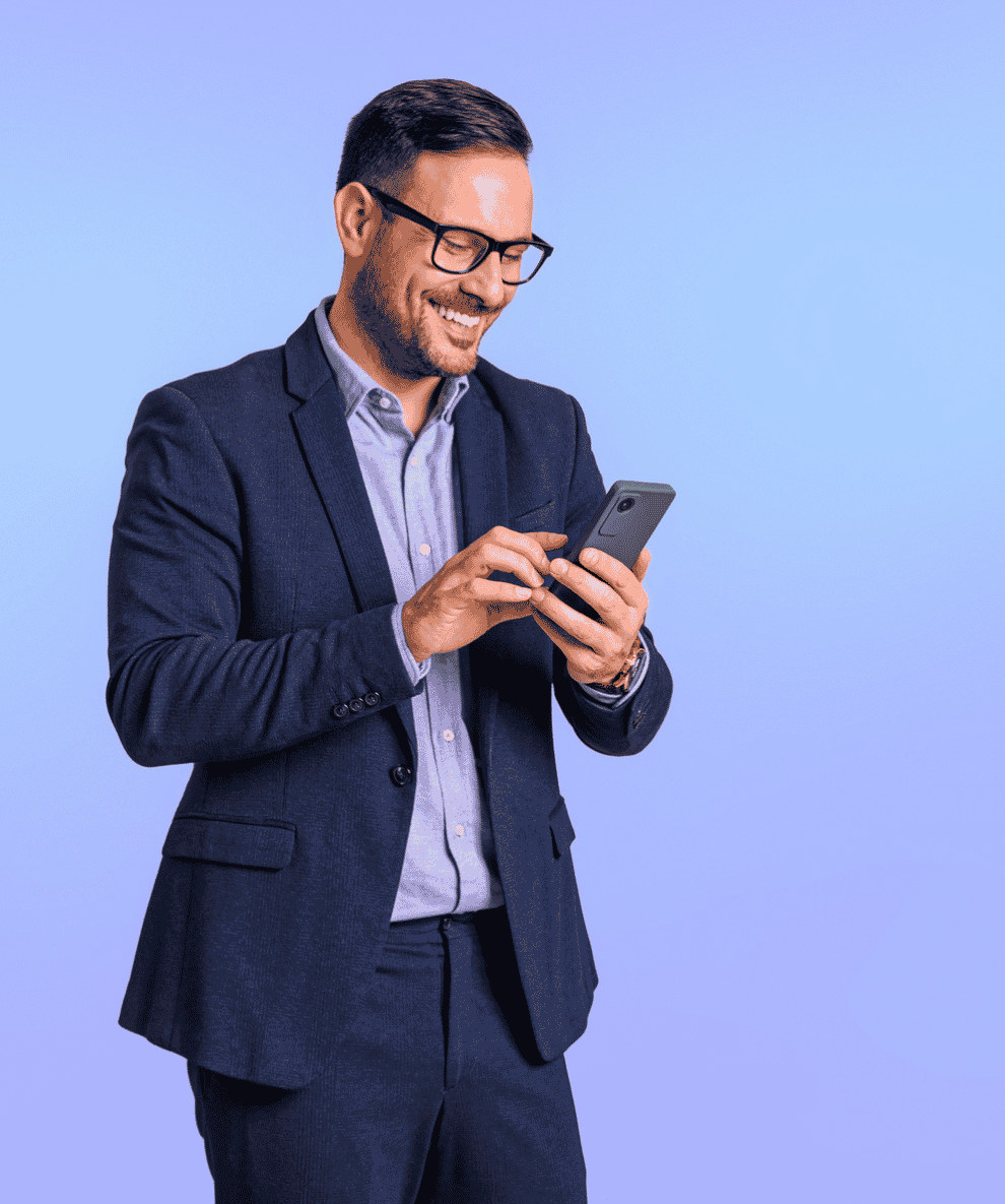 Homme d'affaires souriant utilisant un smartphone sur fond bleu uni.