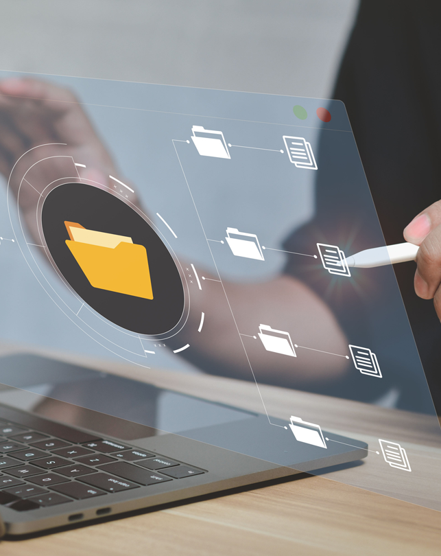 Main manipulating digital file folders and documents interface above laptop on a wooden desk.
